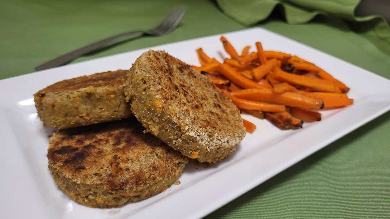 burger di lenticchie pronti sul piatto con un contorno di carote