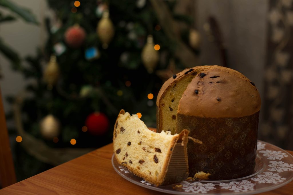 panettone tagliato su tavola natalizia con albero di natale sullo sfondo