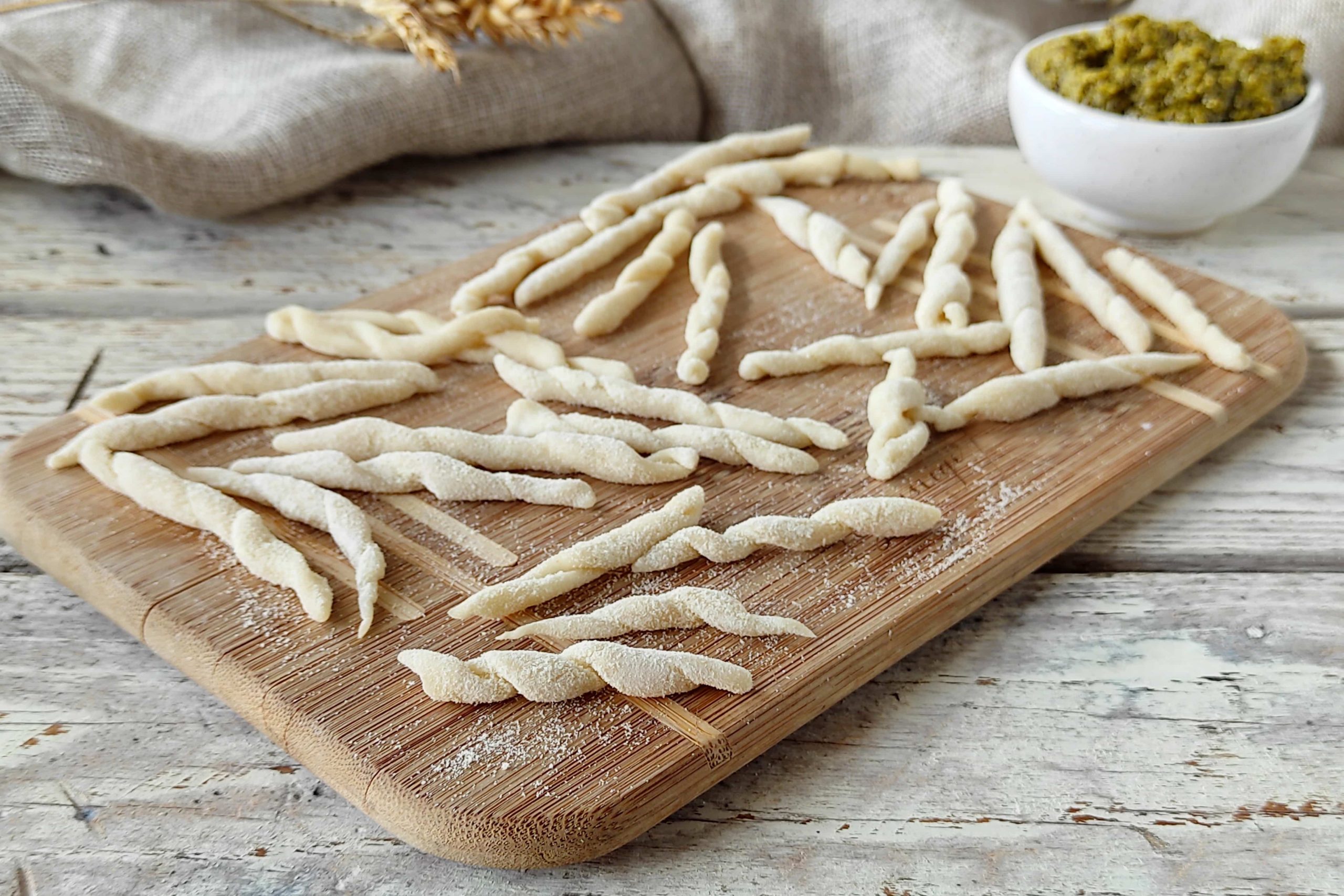 Tagliere di legno con trofie liguri fatte in casa con la ricetta e la tecnica tradizionale della Liguria