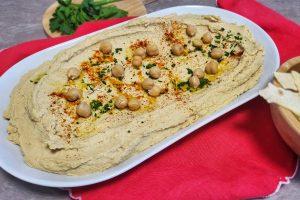 piatto ovale con crema di ceci, paprika e prezzemolo, su tovaglia rossa accompagnato da piadina croccante
