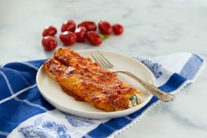 due cannelloni al sugo con una forchetta su un piatto