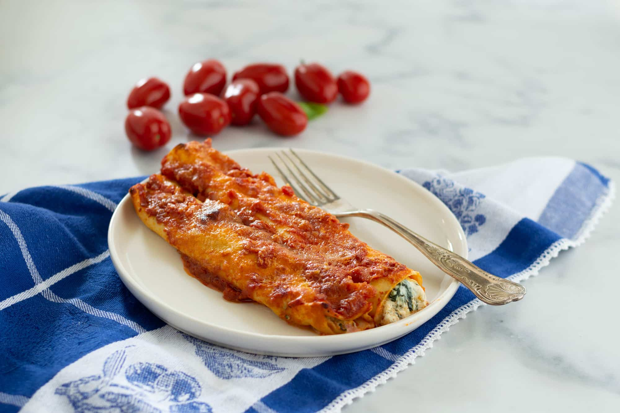 due cannelloni al sugo con una forchetta su un piatto