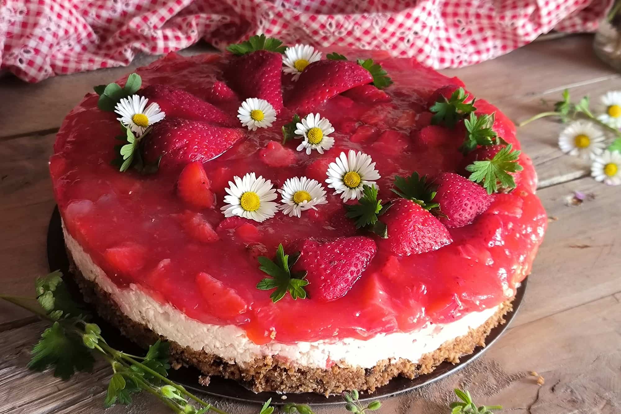 torta a strati con biscotto, strato bianco con panna e strato superiore rosso con fragole e fiori