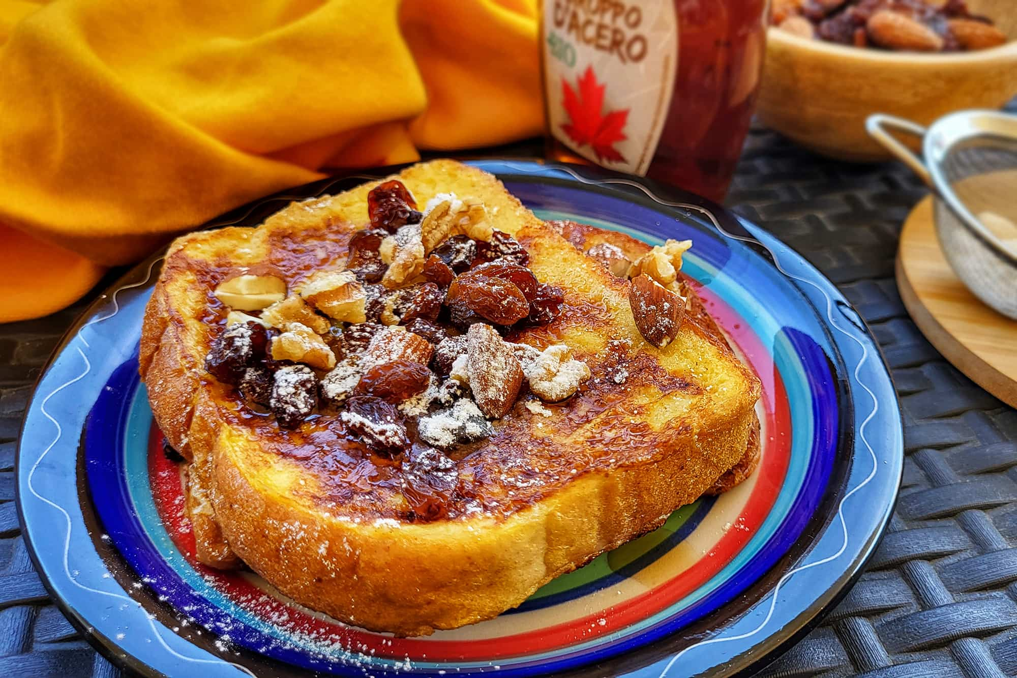 fette di pan brioche fritte e condite con sciroppo d'acero e frutta secca, su un piatto azzurro