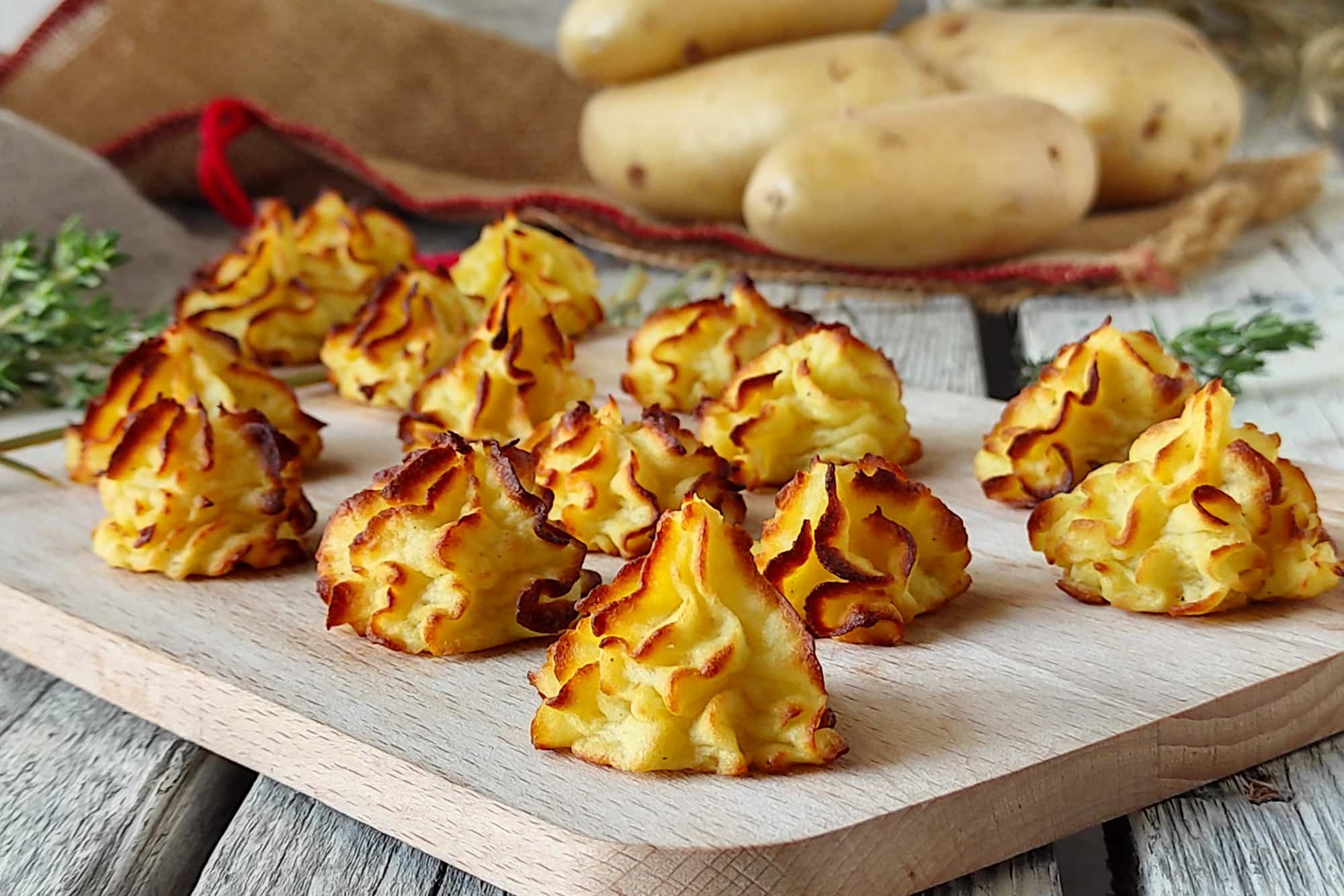 ciuffetti di patate duchessa al forno su un tagliere di legno