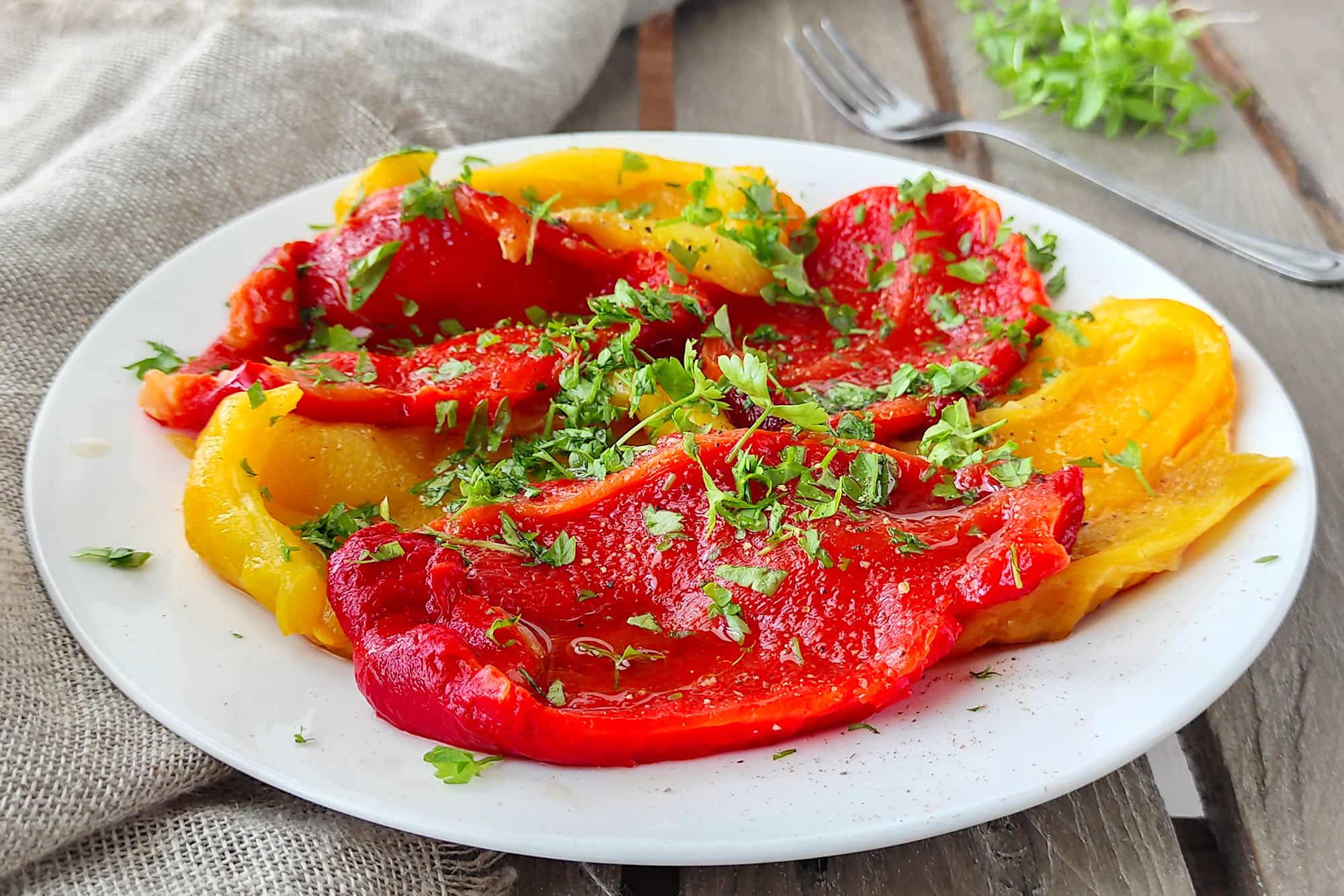 peperoni gialli e rossi conditi con prezzemolo su un piatto bianco