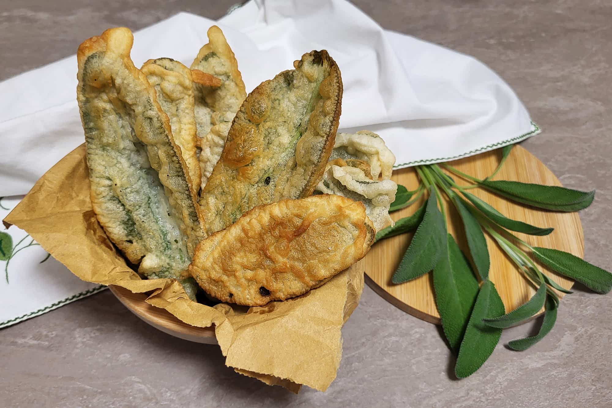 foglie di salvia con pastella fritte all'interno di un foglio di carta assorbente per frittura su un tavolo