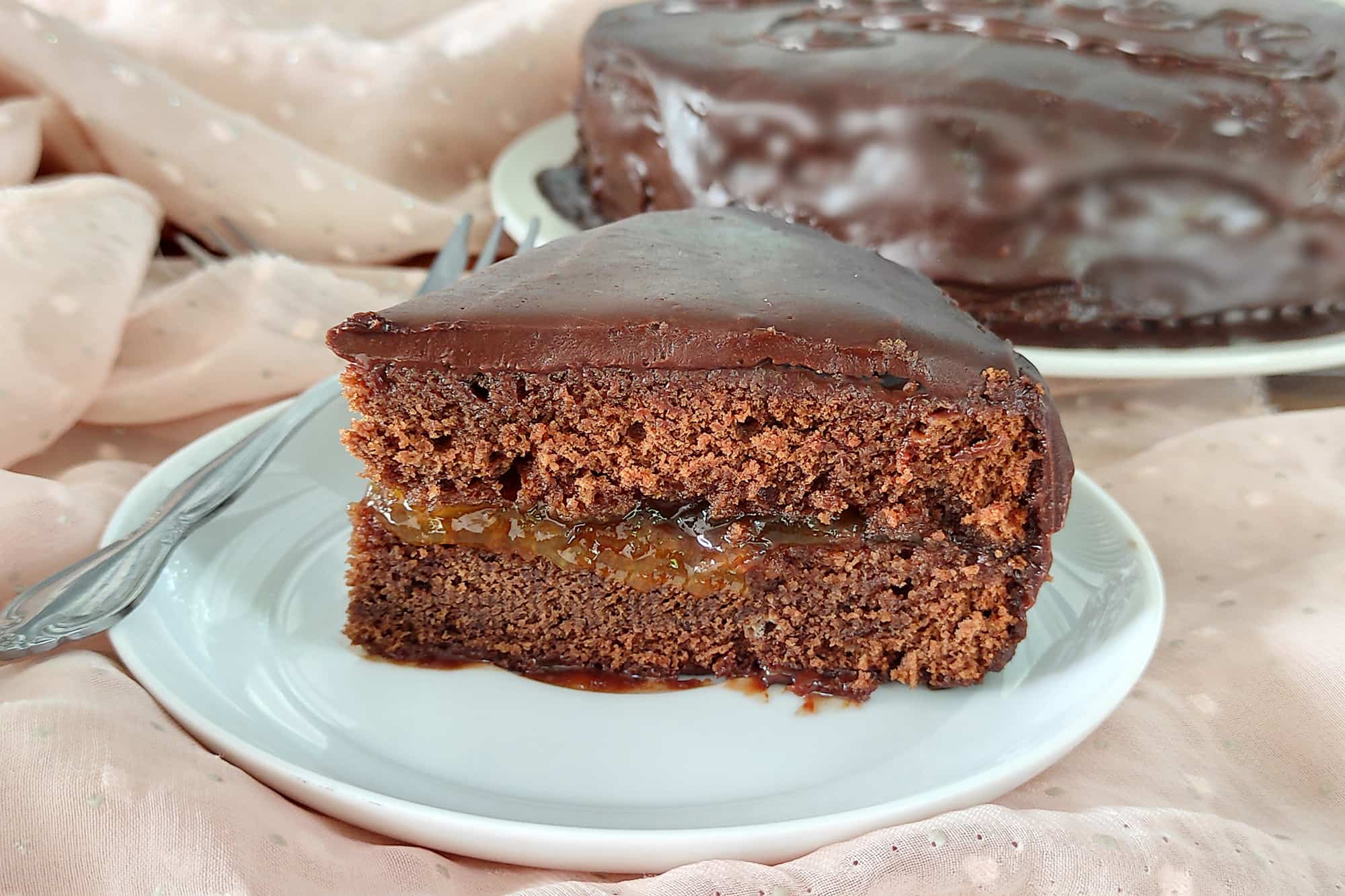 fetta di torta al cioccolato con cioccolato e marmellata, su un piatto bianco