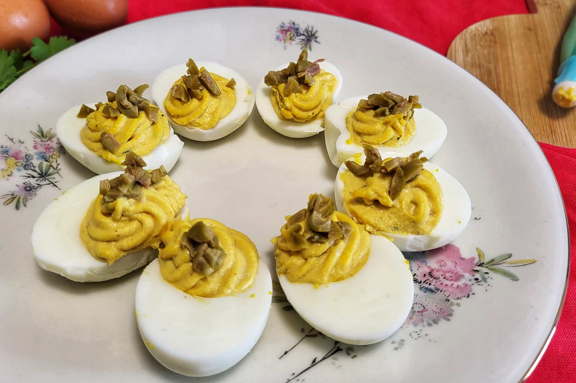 uova sode con ripieno di maionese, tonno e tuorli, condite con olive verdi, su un piatto bianco