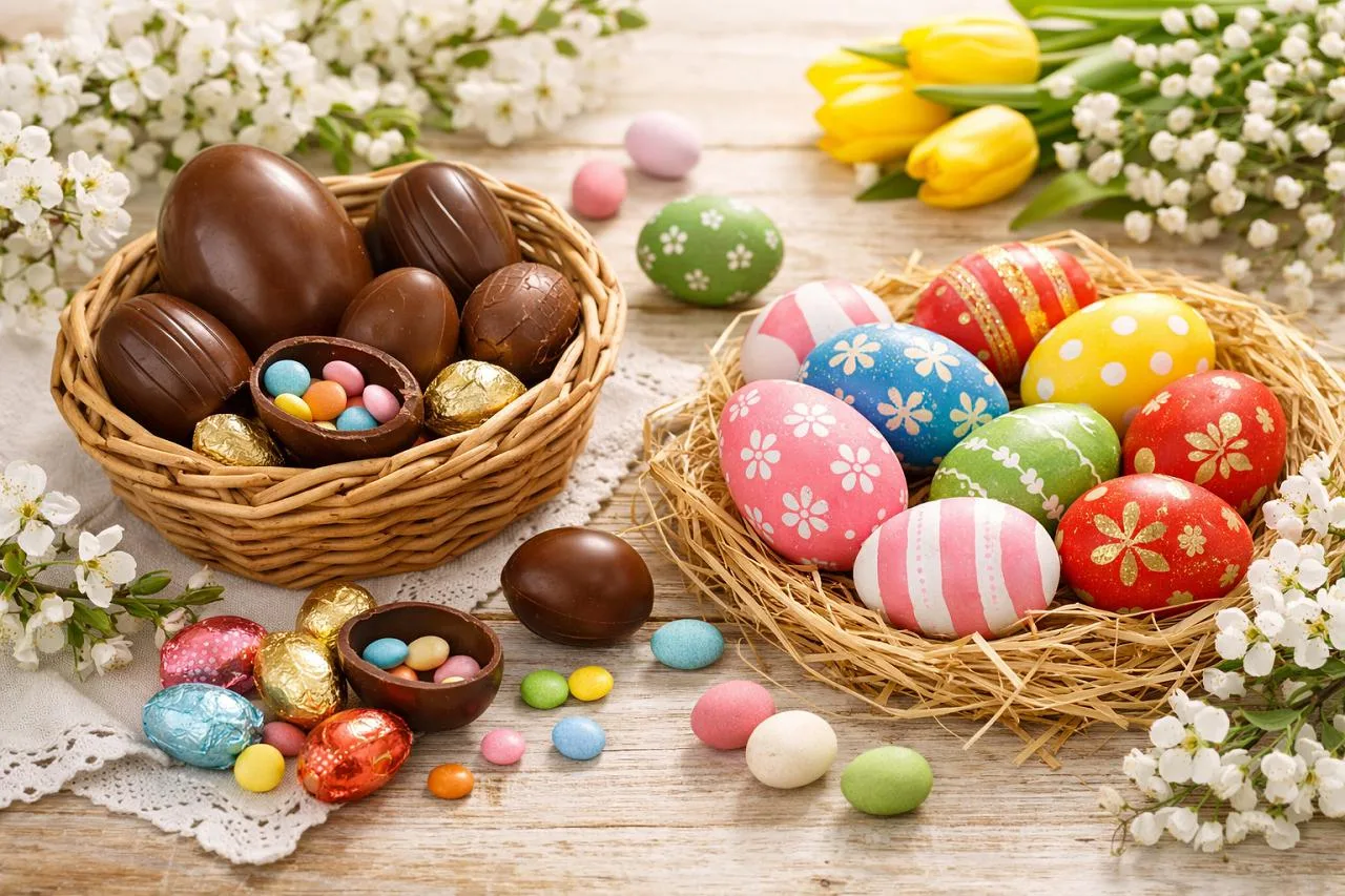 Uova di Pasqua di cioccolato e uova decorate colorate con fiori su tavolo primaverile