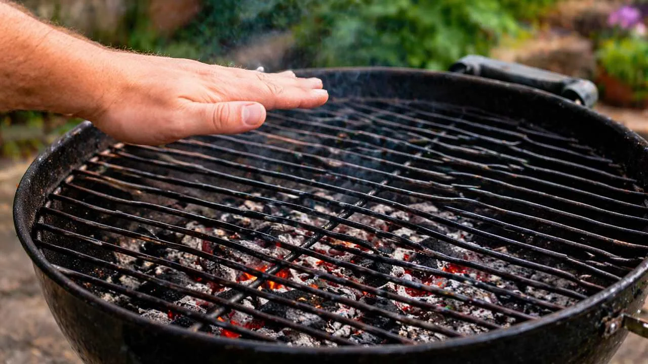 Mano sopra la griglia per controllare la temperatura della brace prima di iniziare a cucinare